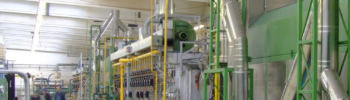 Photo de trois personnes marchant devant des machines en traversant une usine.